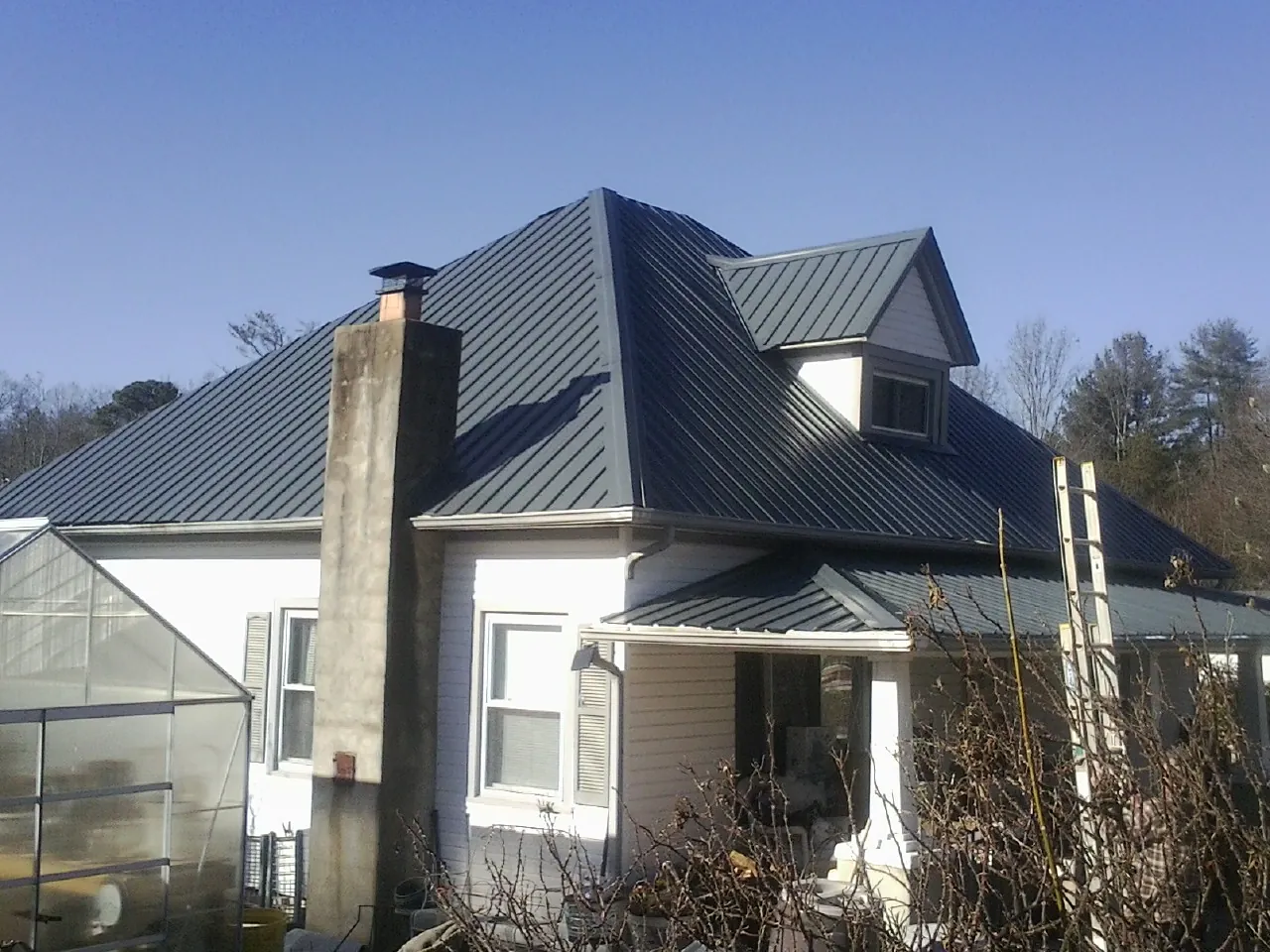Dark blue standing seam metal roof on a white farmhouse with dormer — Slate & Tile Roof Repair by Roofing Brothers in Bergton