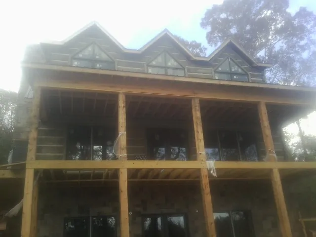 Dormers and porch framing on a large log home under construction — Roof Coating work by our crew in Bergton