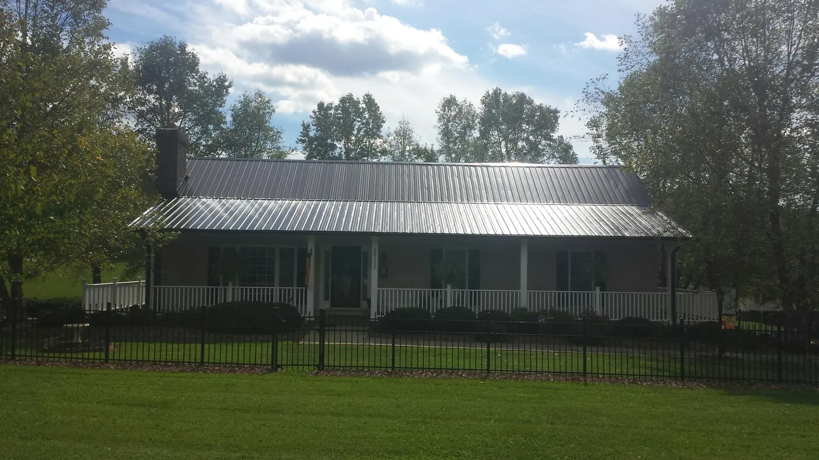 Gray metal roof on a brick ranch with a full width front porch — Gutter Guard Installation work by our crew in Bergton