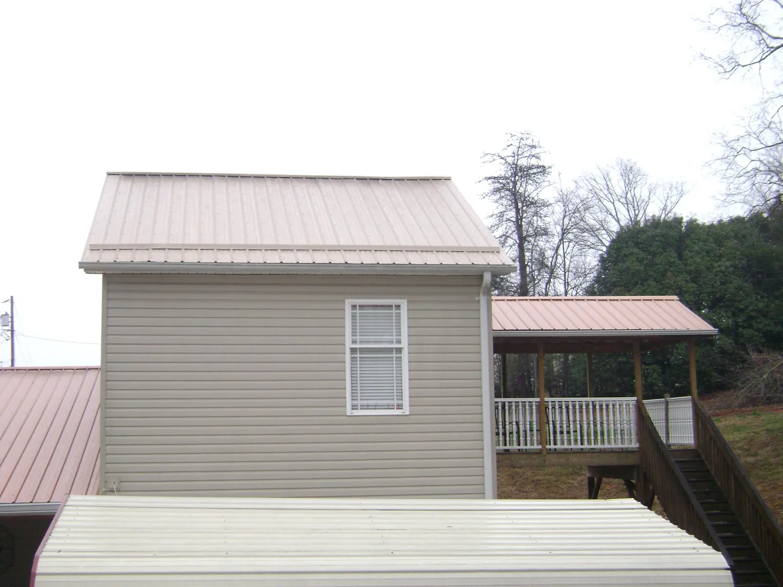 Tan metal roofs on a two story addition and attached porch, from a Roof Replacement job in Bergton