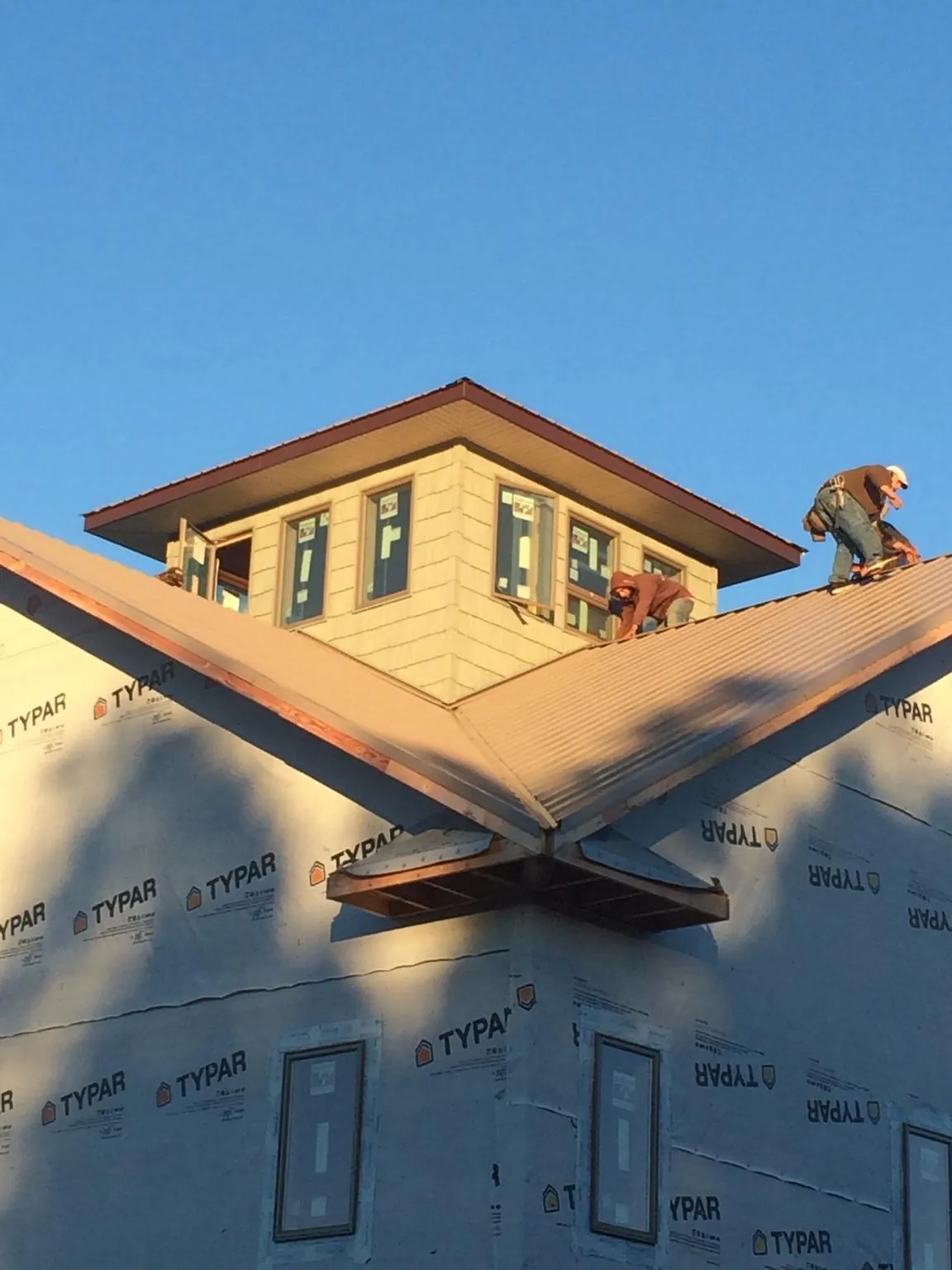 Roofers working around a rooftop cupola on a new metal roof at sunset — Roof Waterproofing in Bergton by Roofing Brothers